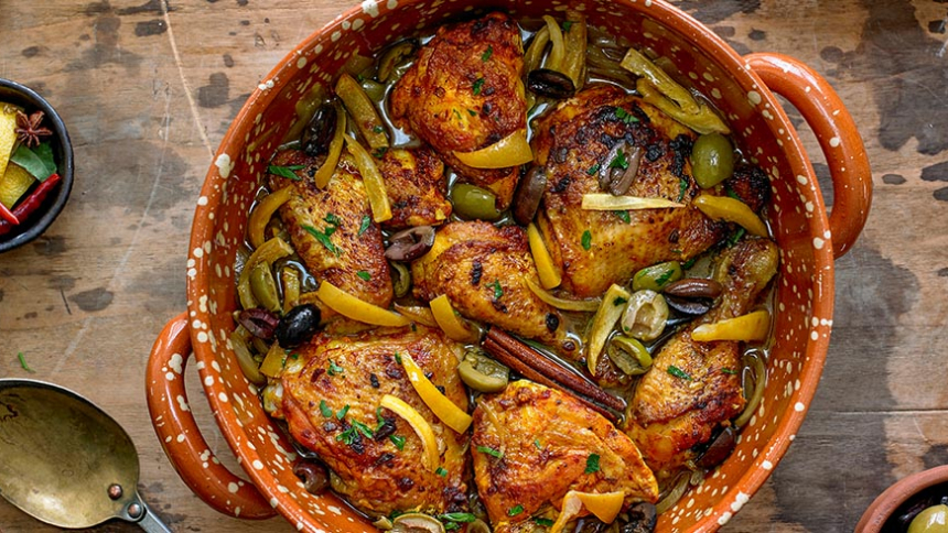 Chicken Tagine with Calamata Olives, Cracked Green Olives and Preserved Lemons in a pot on wooden table